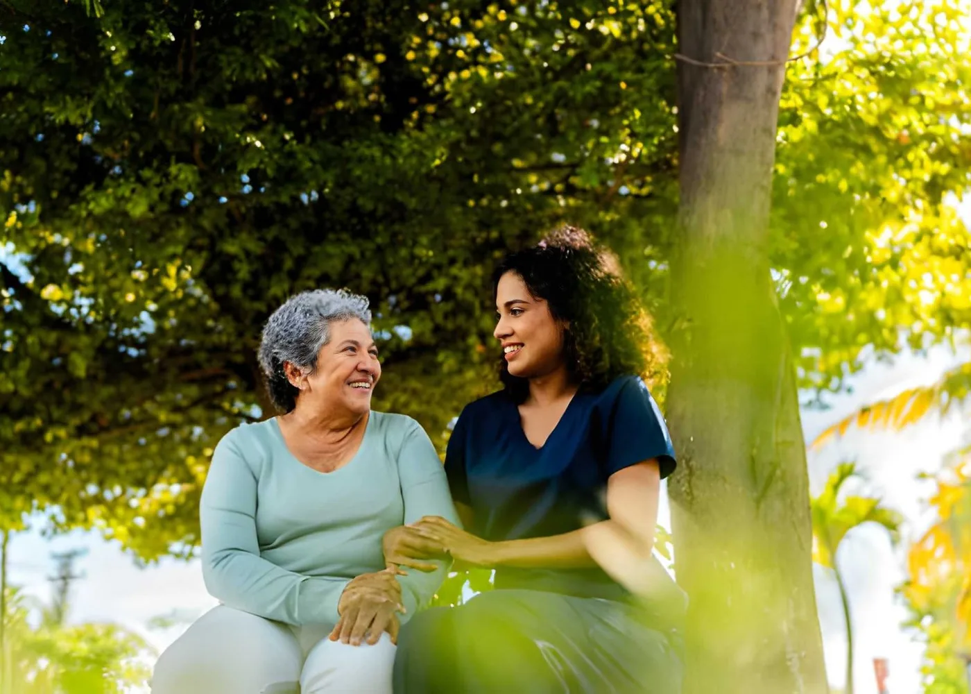An older woman and caregiver sharing a relaxed conversation outdoors