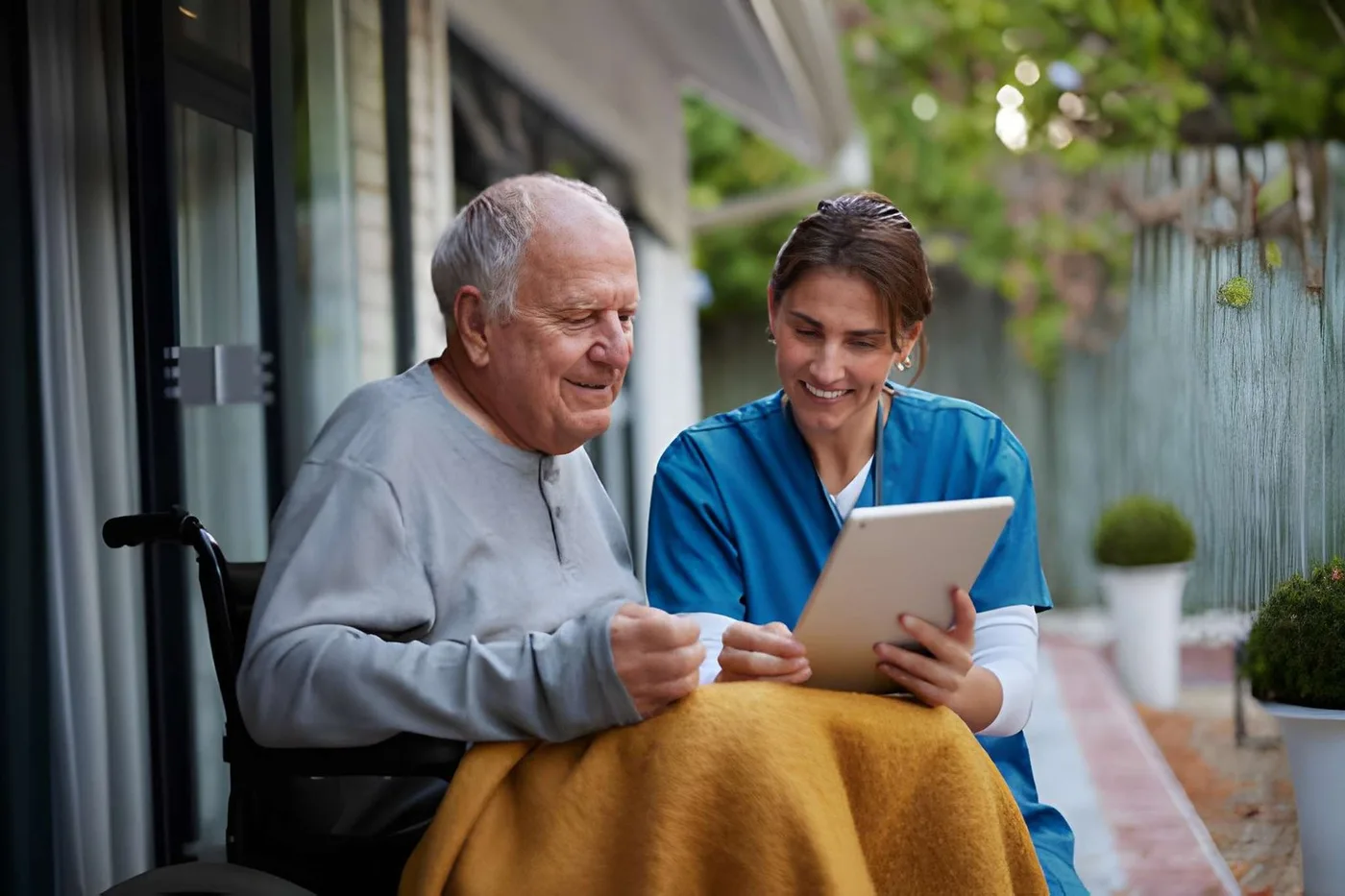An older man and caregiver reviewing information on a tablet